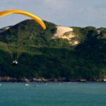 Praticante de parapente sobrevoa a praia de Ponta Negra, a mais turística de Natal (RN). Ao fundo, o Morro do Careca, cartão postal da capital potiguar