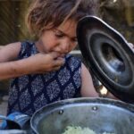 Menina palestina come arroz distribuído por cozinha solidária em Gaza