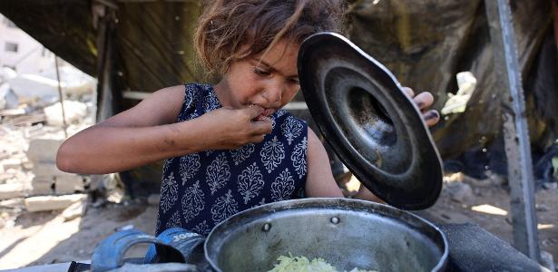 Menina palestina come arroz distribuído por cozinha solidária em Gaza