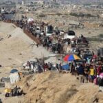 Palestinos deslocados seguem para o sul, em uma estrada na área do campo de refugiados de Nuseirat, no centro da Faixa de Gaza